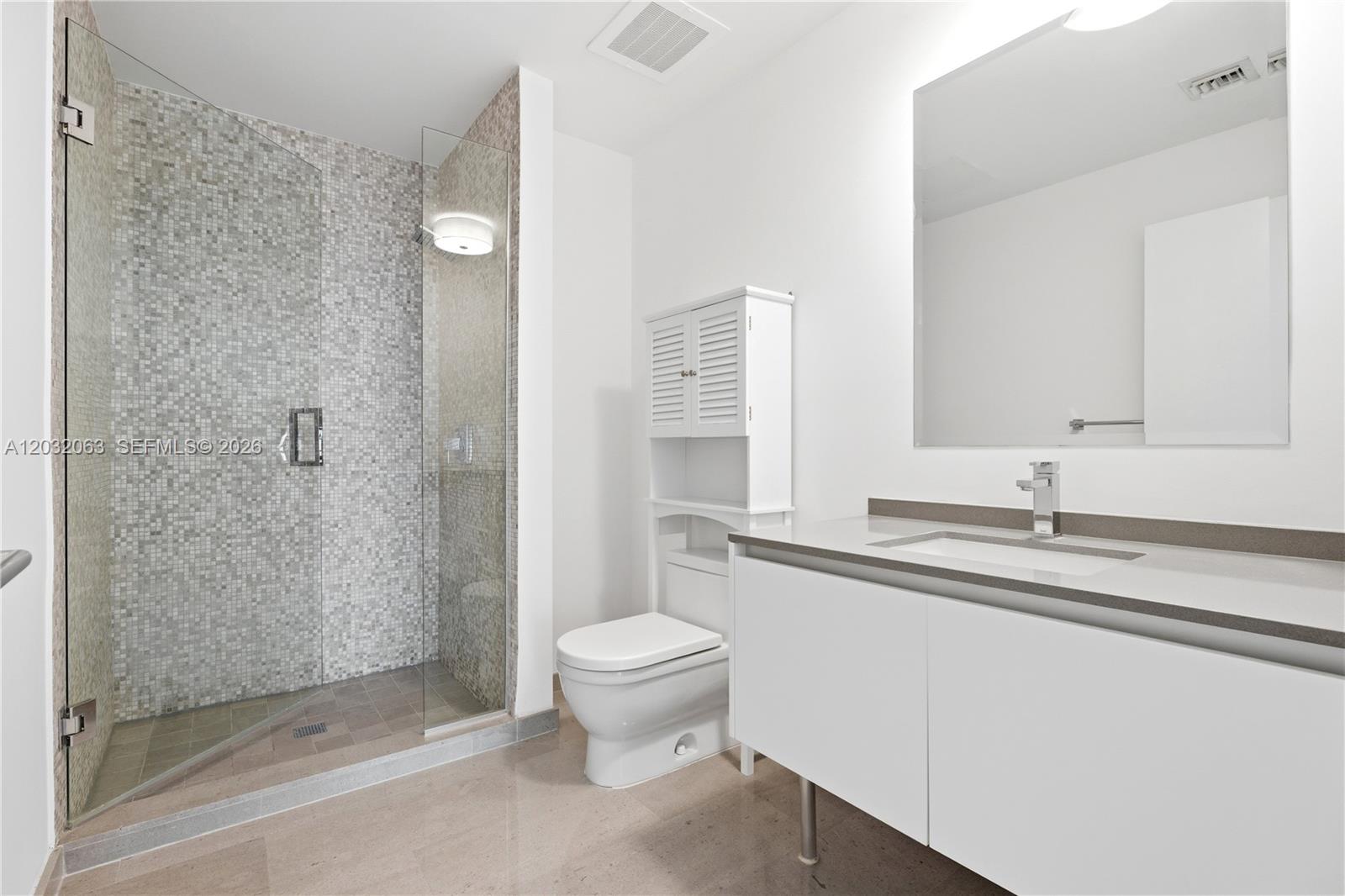 88 Southwest 7th Street, Unit 2302 Miami, FL 33130 - Photo 22 of 26 a bathroom with a granite countertop sink a toilet and a shower