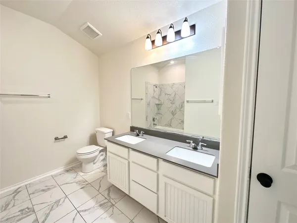 a bathroom with a granite countertop sink a toilet and a mirror