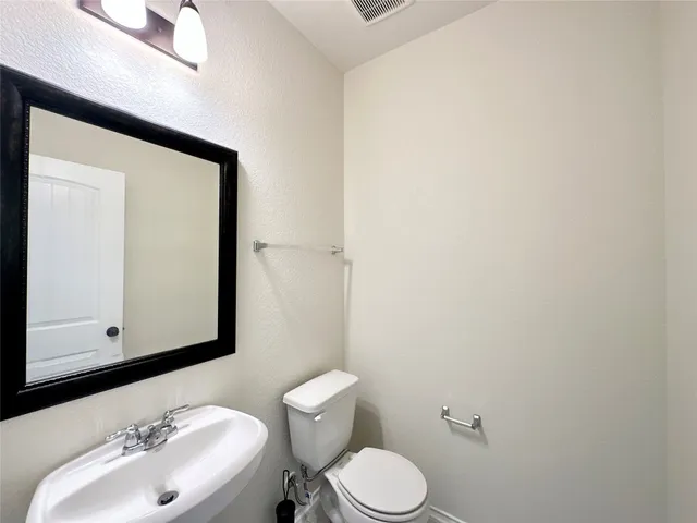 a bathroom with a sink vanity mirror and toilet