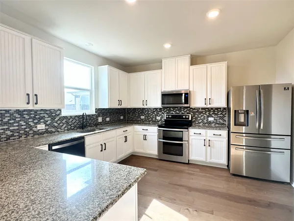 a kitchen with granite countertop white cabinets and stainless steel appliances