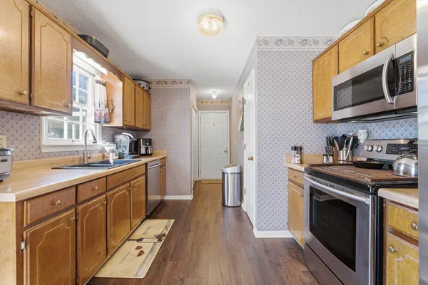 a kitchen with stainless steel appliances granite countertop a stove a sink dishwasher and a microwave oven with wooden floor