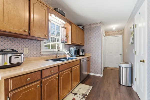 a kitchen with granite countertop stainless steel appliances a sink window and cabinets
