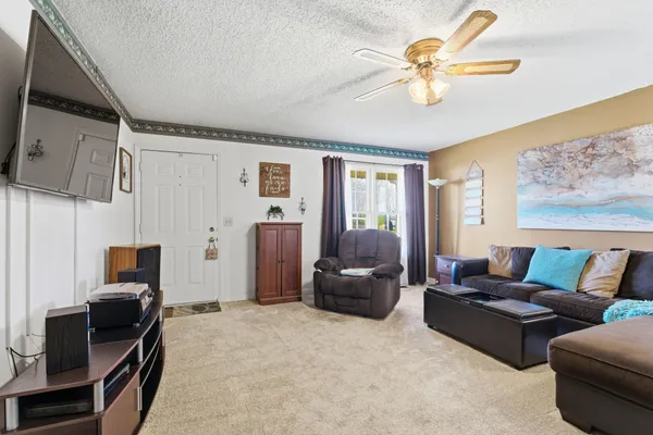 a living room with furniture a ceiling fan and a window