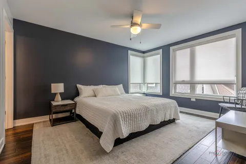 a bedroom with a bed lamp on table and a large window