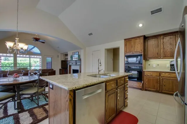a kitchen with a stove a sink a refrigerator and chairs
