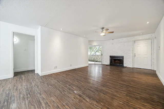 an empty room with wooden floor fireplace and windows