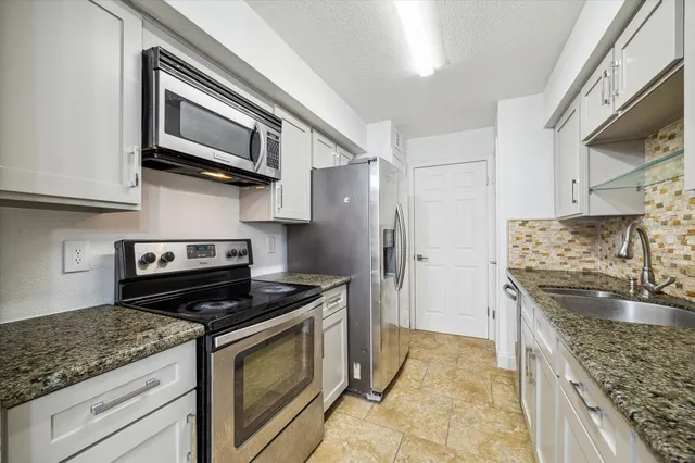 a kitchen with stainless steel appliances granite countertop a stove microwave and refrigerator