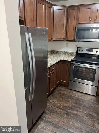 a kitchen with granite countertop a refrigerator and a stove top oven