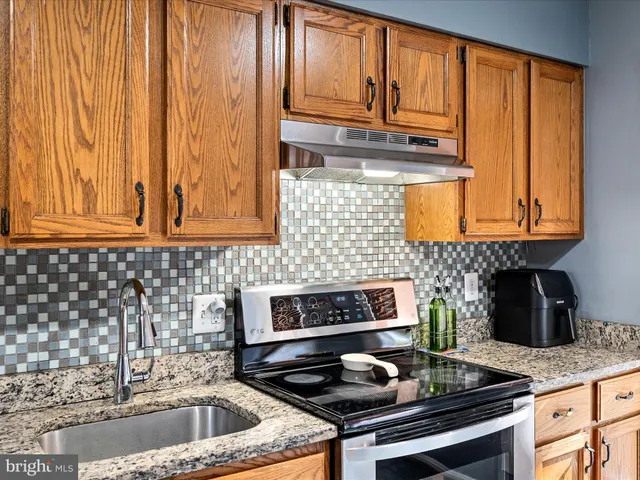 a kitchen with granite countertop wood cabinets stainless steel appliances and a sink