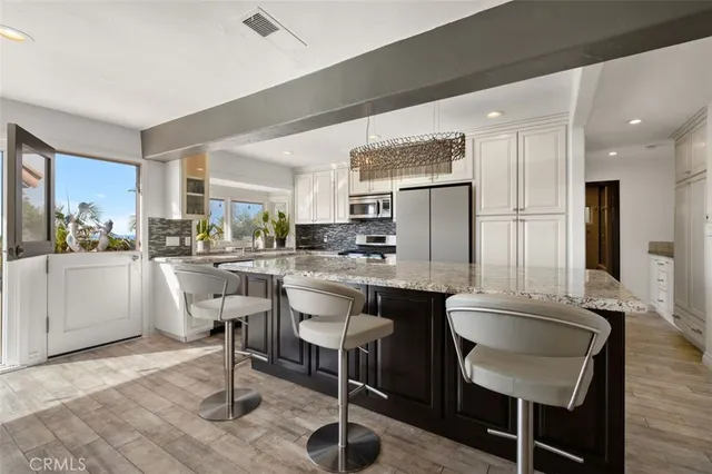 a large kitchen with kitchen island granite countertop stainless steel appliances lots of counter space dining table and chairs