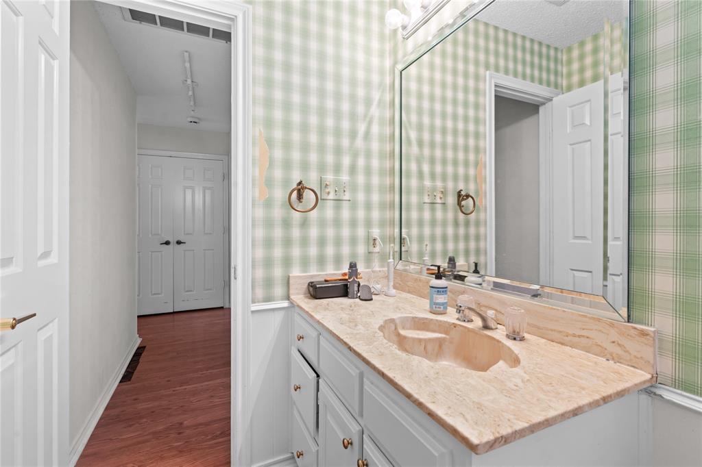 3506 Ruidoso Drive Arlington, TX 76017 - Photo 32 of 37 Bathroom vanity featuring a light-colored countertop with an integrated sink, white cabinetry with brass-toned hardware, and a large wall-mounted mirror