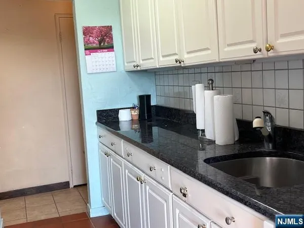 a kitchen with granite countertop a sink and a white cabinets