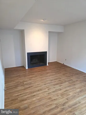 a view of empty room with wooden floor and fireplace