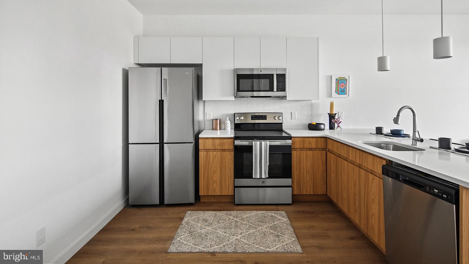 a kitchen with stainless steel appliances granite countertop a refrigerator a stove a sink and a microwave