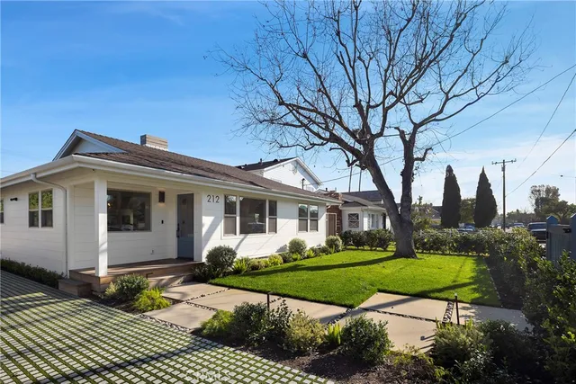 a front view of a house with a garden and trees