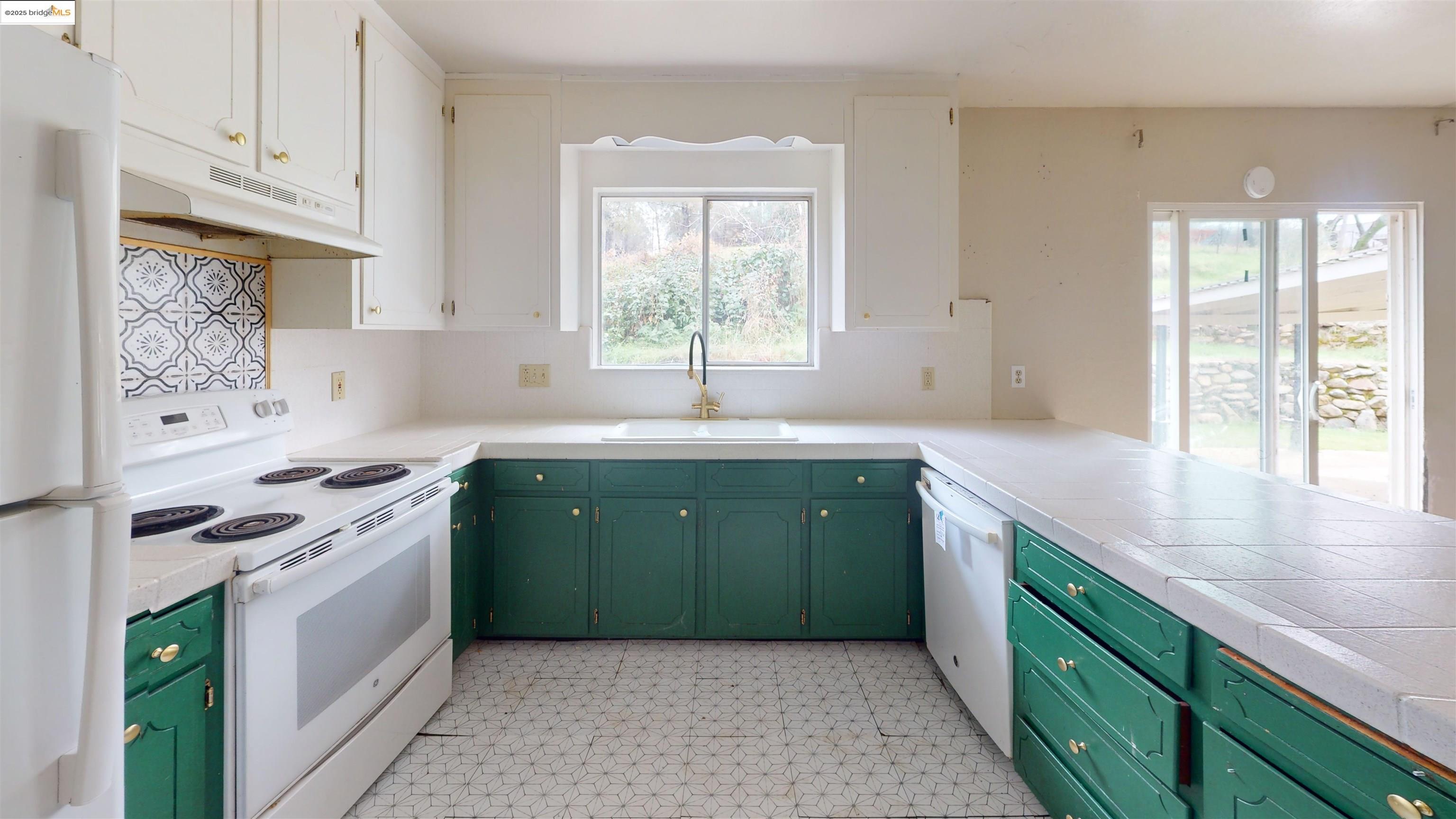 19817 Via Redonda Road Sonora, CA 95370 - Photo 6 of 23 Kitchen featuring green cabinets, white appliances, tile counters, light flooring, and under cabinet range hood
