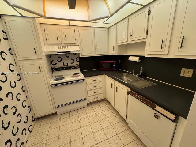 a kitchen with stainless steel appliances a stove a sink and white cabinets