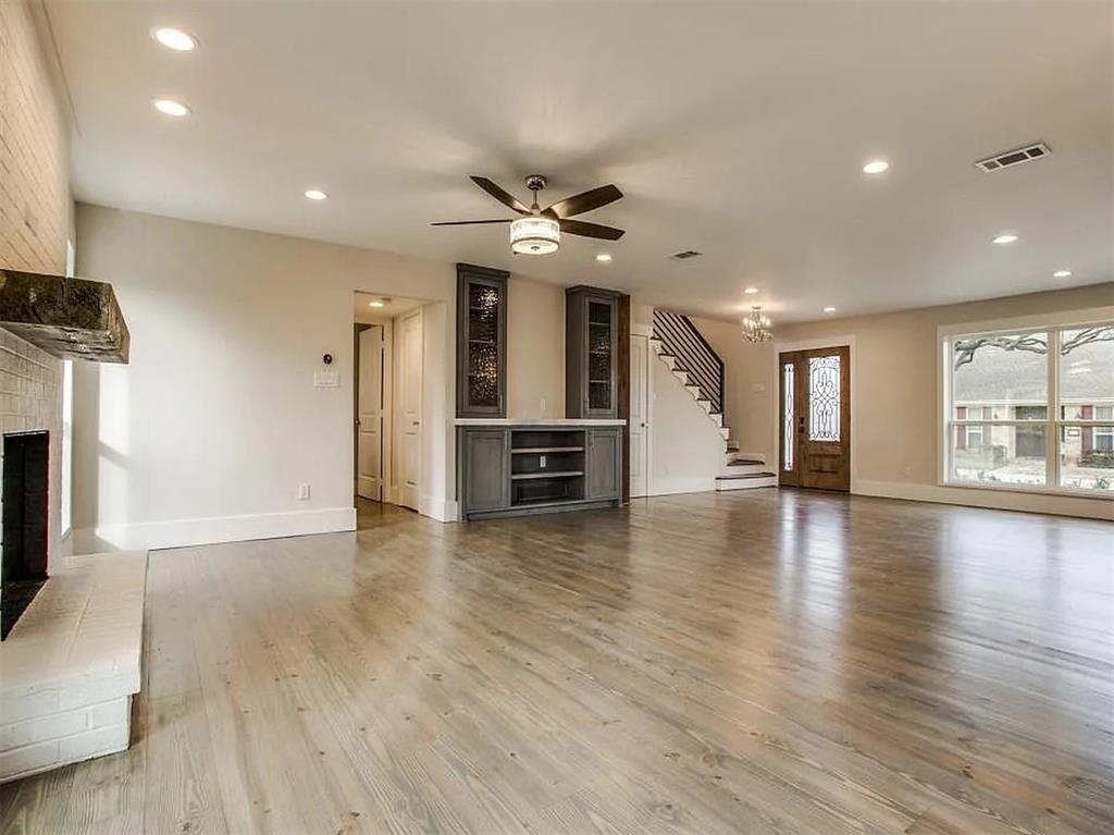 4310 Forest Bend Road Dallas, TX 75244 - Photo 8 of 34 an empty room with wooden floor a ceiling fan a fireplace and windows