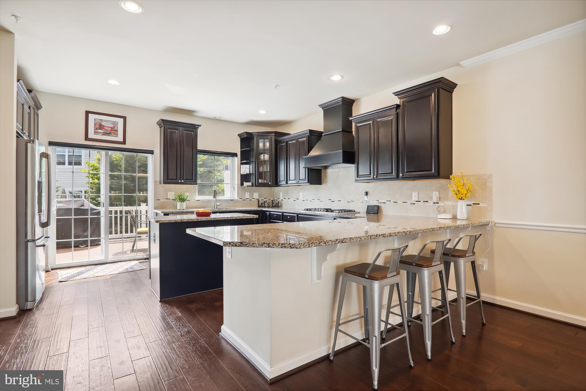 a kitchen with stainless steel appliances kitchen island granite countertop a stove a refrigerator a sink and a dining table with wooden floor