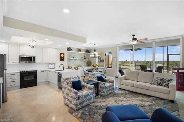 a living room with furniture kitchen area and a large window