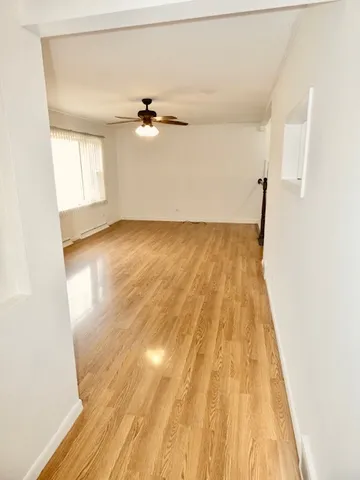 a view of a room with wooden floor and ceiling fan