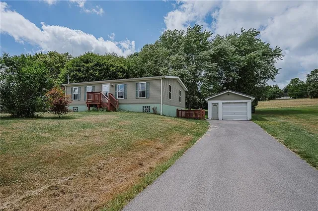 a front view of house with yard and trees in the background