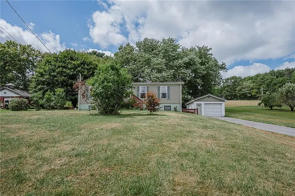 a front view of a house with a yard and trees