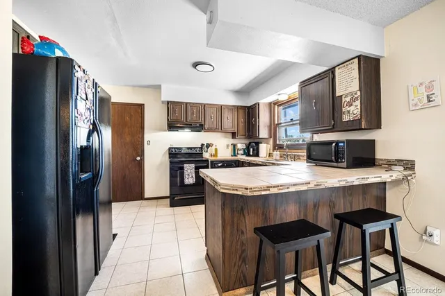 a kitchen with stainless steel appliances granite countertop a table chairs refrigerator and microwave