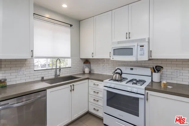 a kitchen with white cabinets sink and appliances