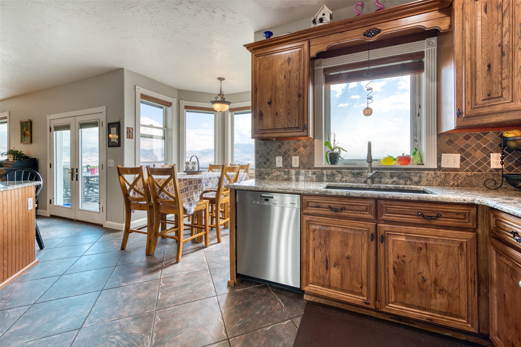 16374 Folsom Road Florence, MT 59833 - Photo 30 of 98 Kitchen with brown cabinetry, dishwasher, light stone countertops, and a textured ceiling