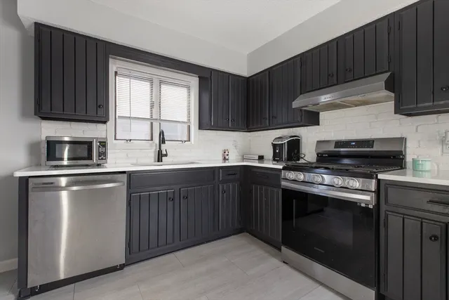 a kitchen with stainless steel appliances granite countertop a stove a sink dishwasher and a microwave oven with cabinets