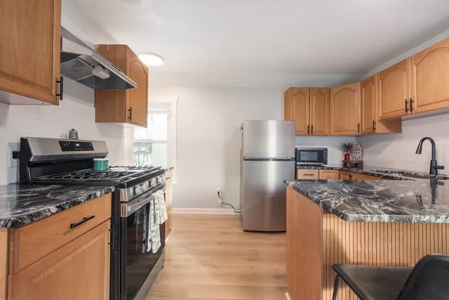 a kitchen with stainless steel appliances granite countertop a stove top oven a refrigerator a sink and dishwasher