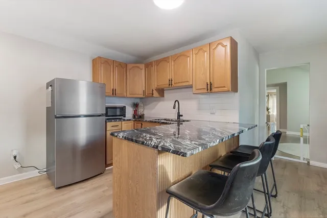 a kitchen with stainless steel appliances granite countertop a refrigerator a sink a stove a dining table and chairs