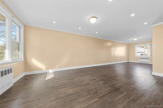 a view of empty room with wooden floor and windows