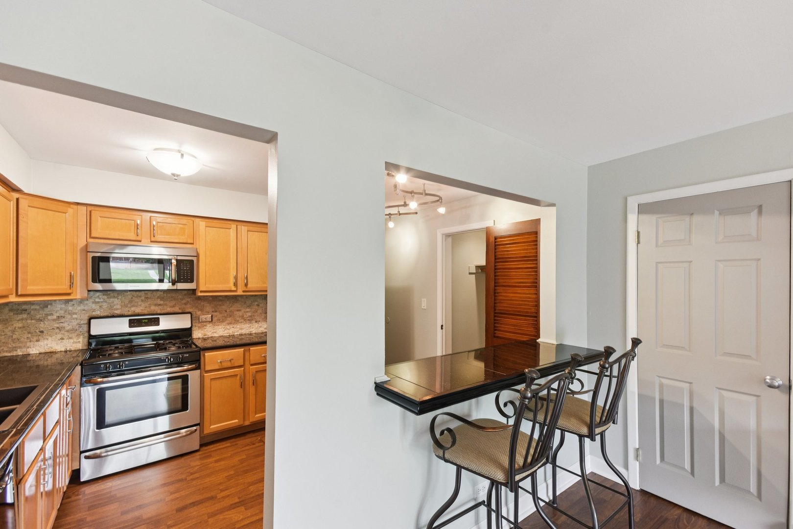 493 McHenry Road, Unit 1B Wheeling, IL 60090 - Photo 8 of 30 a kitchen with stainless steel appliances a stove top oven a sink a dining table and chairs with wooden floor