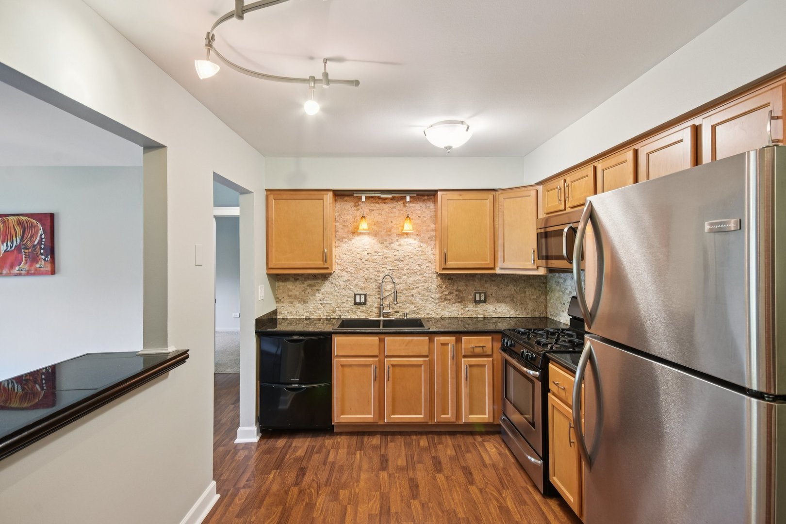 493 McHenry Road, Unit 1B Wheeling, IL 60090 - Photo 9 of 30 a kitchen with stainless steel appliances granite countertop a refrigerator a sink dishwasher a stove and white countertops with wooden floor