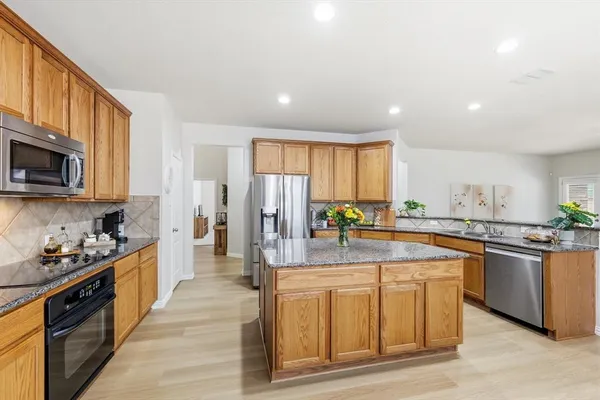 a kitchen with kitchen island granite countertop a table chairs stove and microwave
