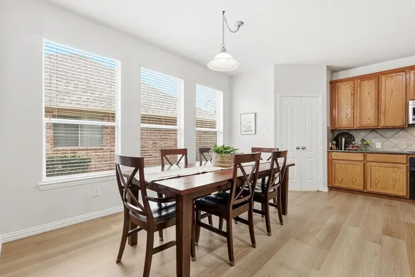 a kitchen with stainless steel appliances granite countertop a stove top oven a sink dishwasher a refrigerator and a dining table with wooden floor