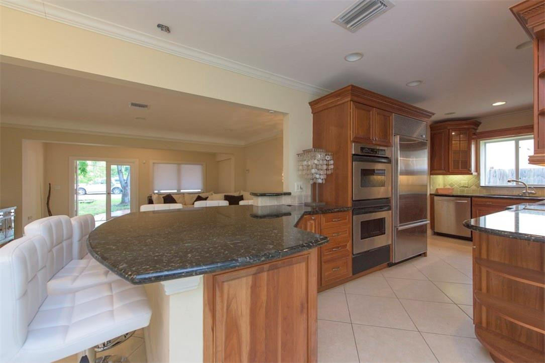 3405 Leigh Road Pompano Beach, FL 33062 - Photo 13 of 35 a kitchen with stainless steel appliances granite countertop a sink and dishwasher a refrigerator with wooden cabinets
