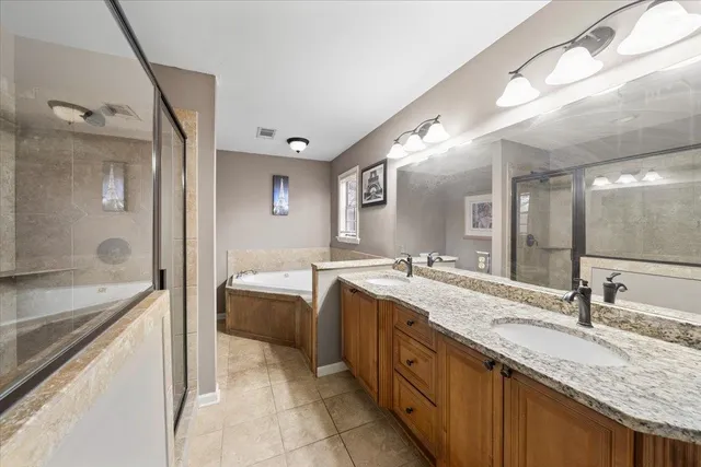 a en suite bathroom with sinks granite countertop tub and a mirror