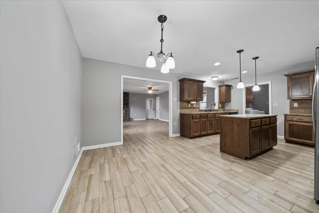 a large kitchen with stainless steel appliances kitchen island granite countertop a large counter top a sink and a refrigerator