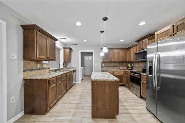 a kitchen with a refrigerator a sink and wooden floor