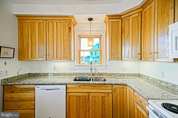 a kitchen with stainless steel appliances granite countertop a stove top oven a refrigerator a sink dishwasher and white cabinets with wooden floor