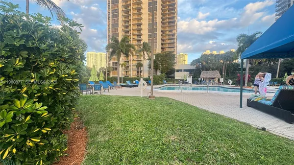 a view of a swimming pool with a lawn chairs and palm trees