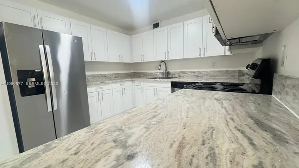 a kitchen with granite countertop a refrigerator and a sink