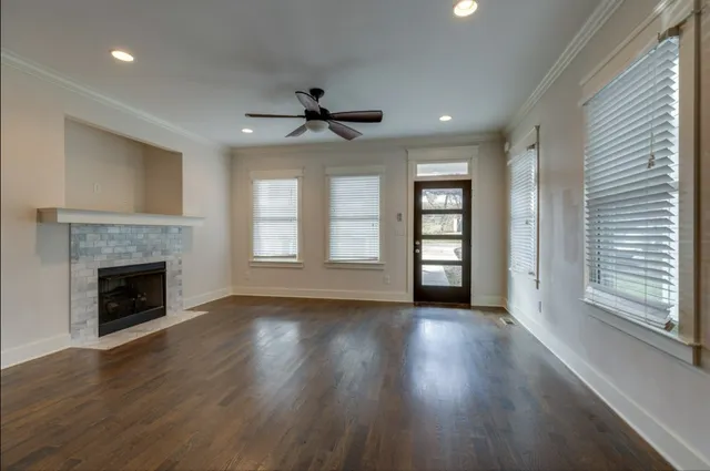 a view of an empty room with wooden floor fireplace and a window