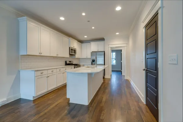 a large kitchen with stainless steel appliances granite countertop a lot of counter space and wooden floors