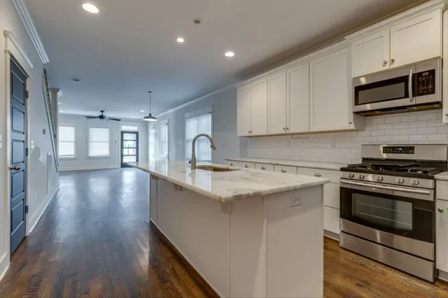 a kitchen with stainless steel appliances granite countertop a stove a sink and a microwave