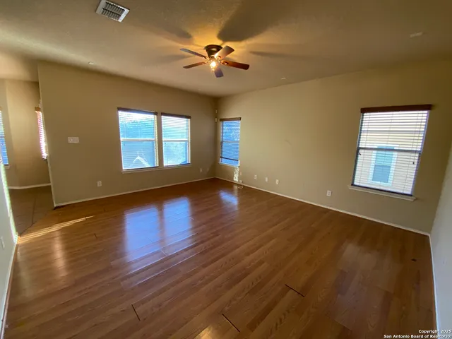 an empty room with wooden floor and windows