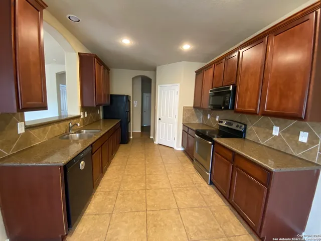 a large kitchen with stainless steel appliances granite countertop a sink stove and refrigerator